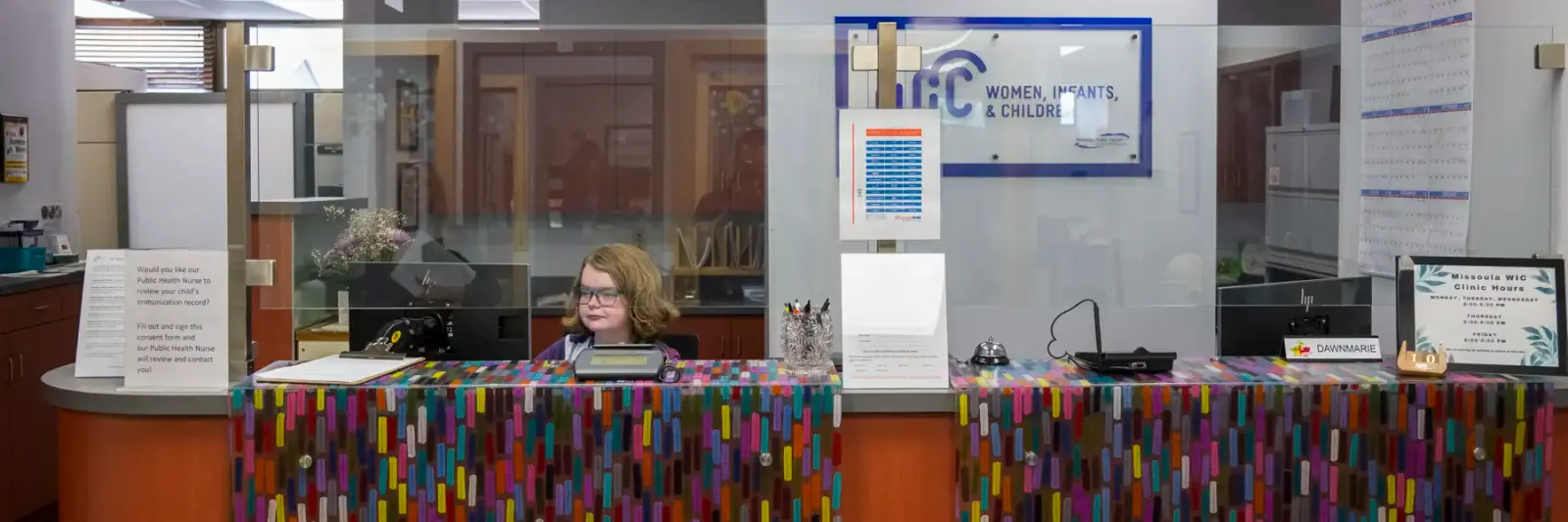 A person sits behind a reception desk at a clinic.