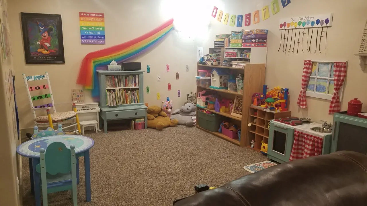 A brightly decorated indoor playroom for children featuring a bookshelf, toy storage, and child-sized furniture.