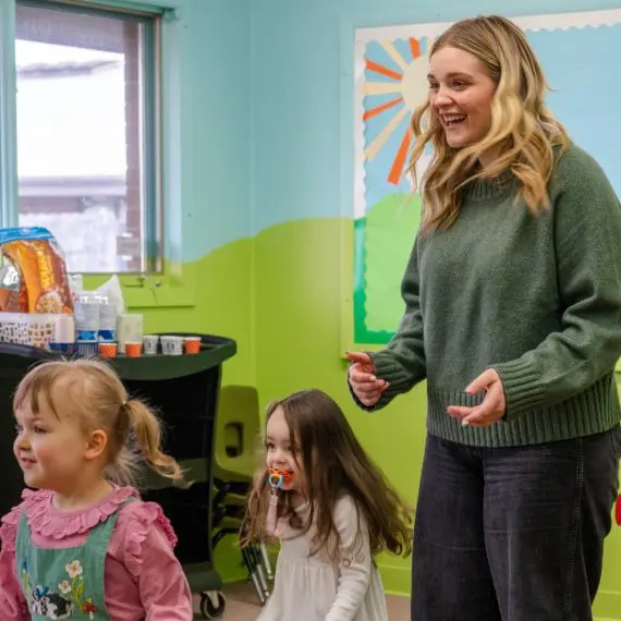 An instructor interacts with children in a classroom setting.