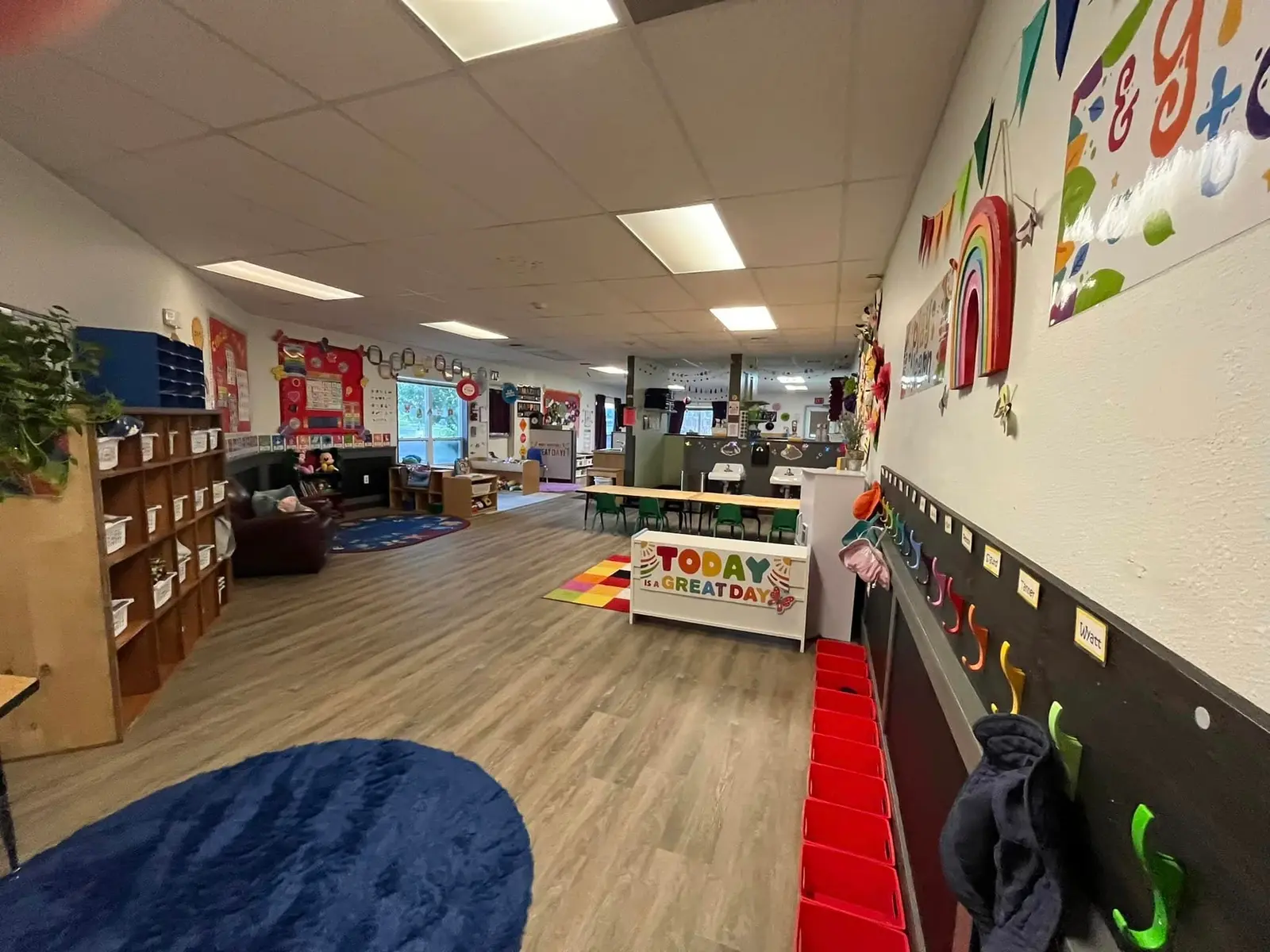 An empty, colorful preschool classroom features cubbies, tables, and a vibrant play area.