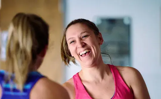 Two adult women are laughing and talking together.