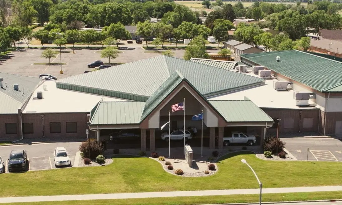 An aerial view of a building with a green metal roof and an adjacent parking lot.