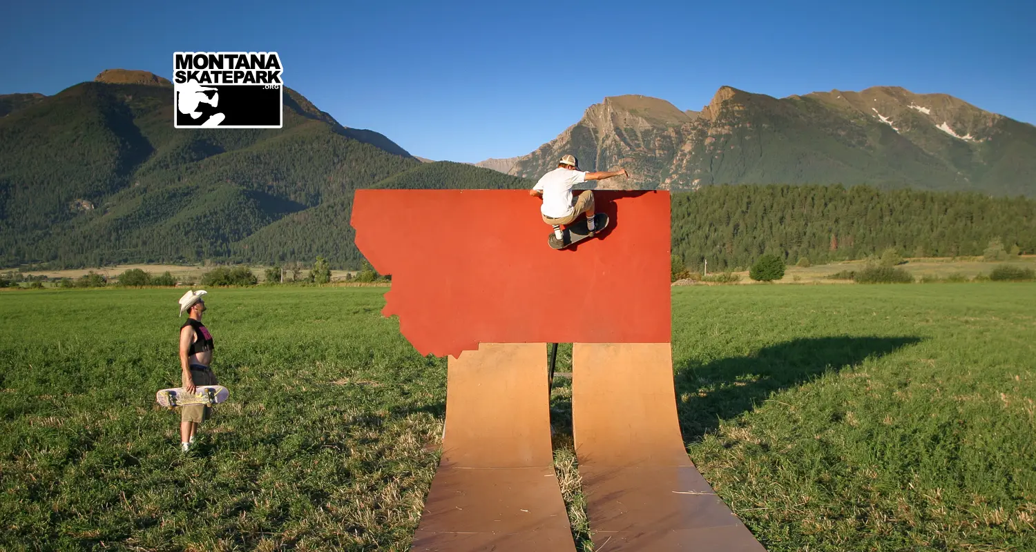 A skateboarder performs a trick on a ramp shaped like a state in a mountain field.