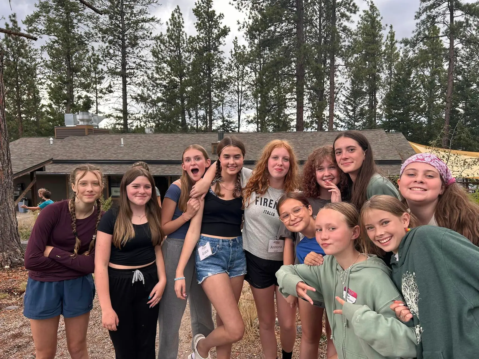 A group of adolescent girls pose together outdoors in front of a building.