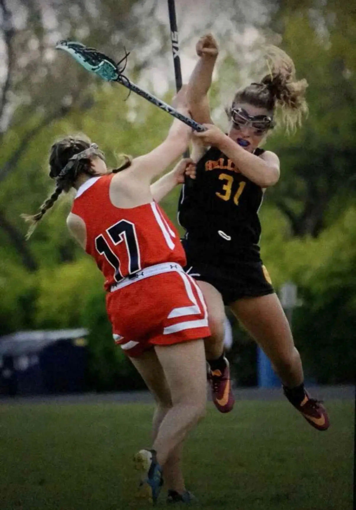 Two lacrosse players compete for the ball on an outdoor field.