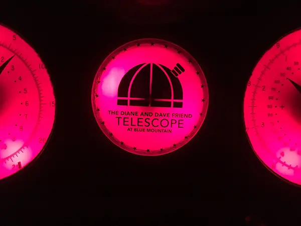 Illuminated circular sign with a dome telescope icon and the text The Diane and Dave Friend Telescope at Blue Mountain.