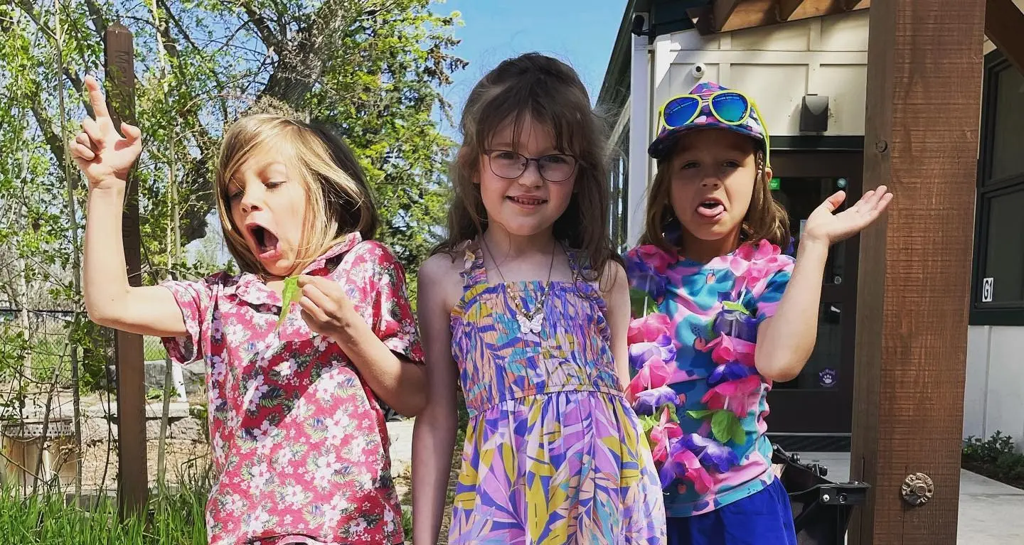 Three children pose together outdoors.