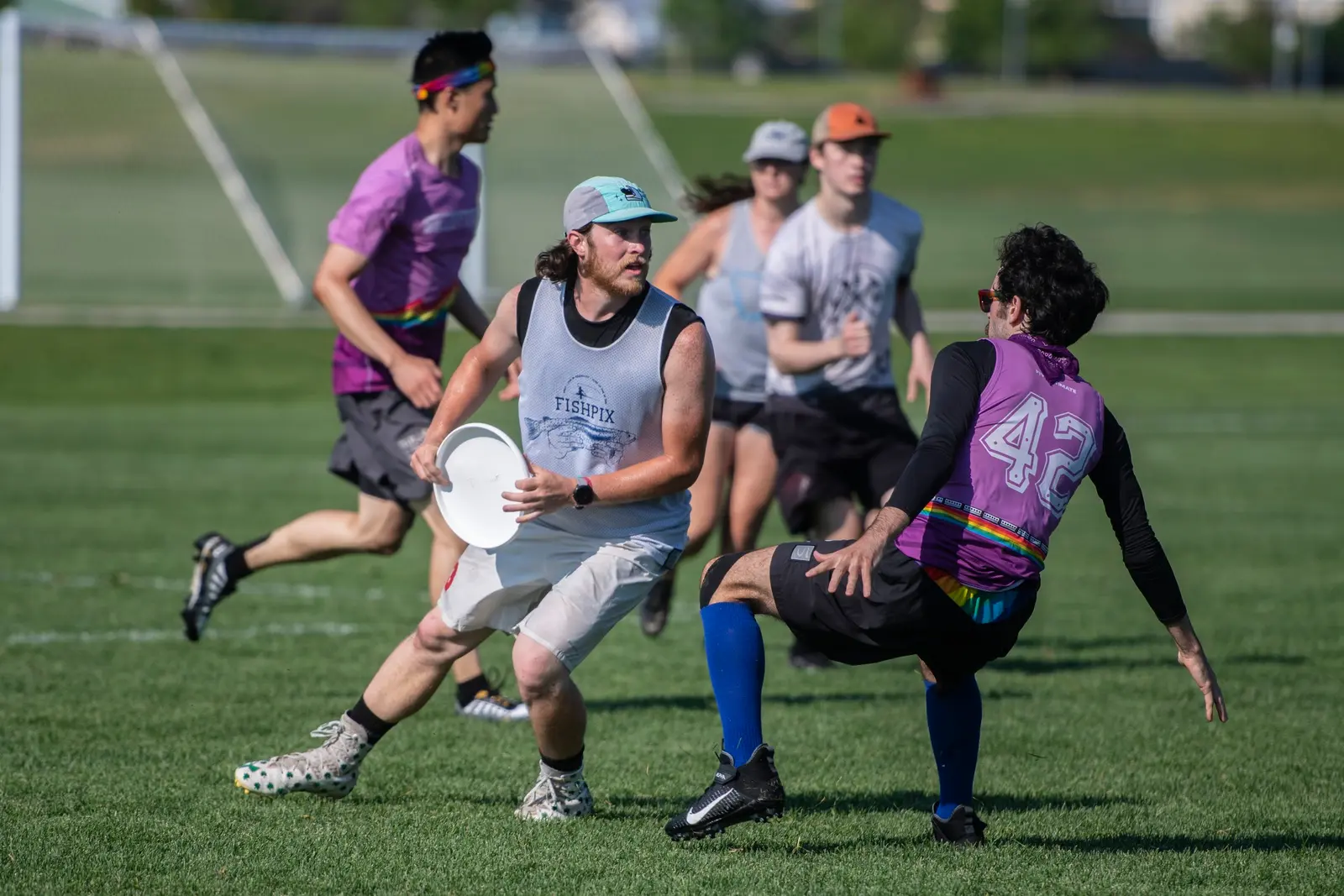 A group of adults plays a game of ultimate frisbee on a grass field.