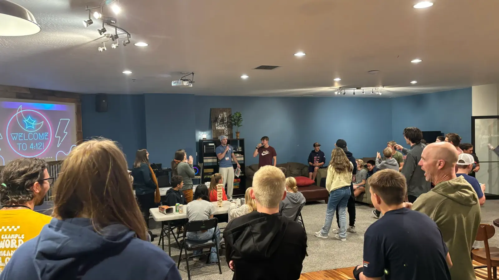 A group of young people and adults are gathered in a room for a youth ministry event.