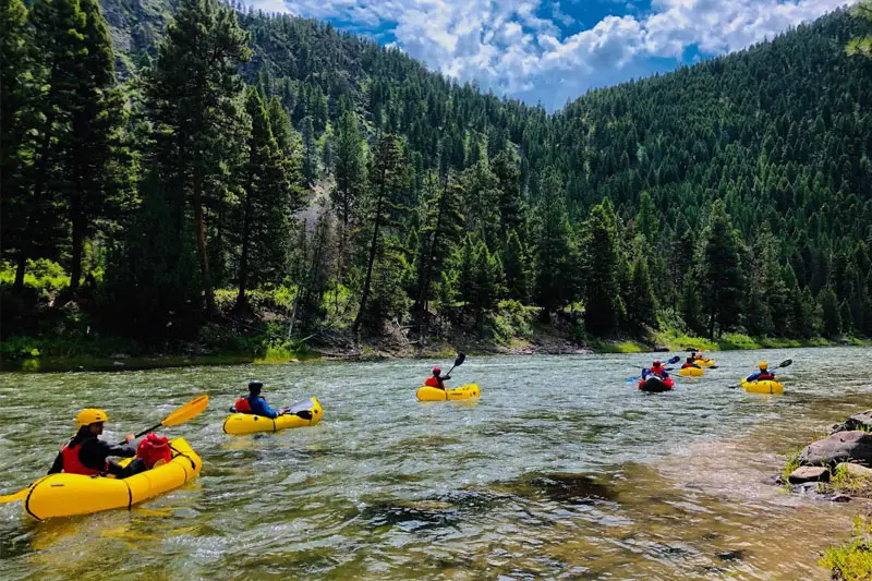 Packrafters paddling down forested mountain river